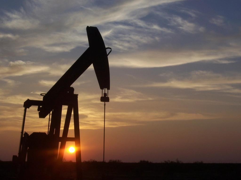 Oil pumpjack operating in an oil field at sunset